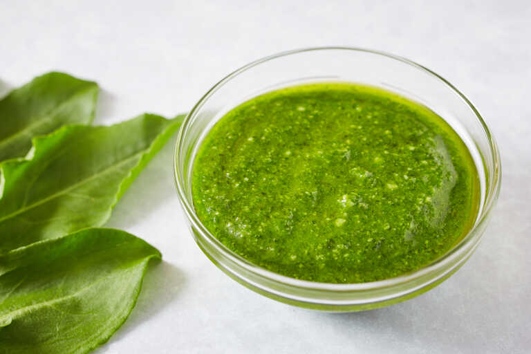 Pesto zo šťaveľa v mištičke s vedľa položenými listami šťavela.